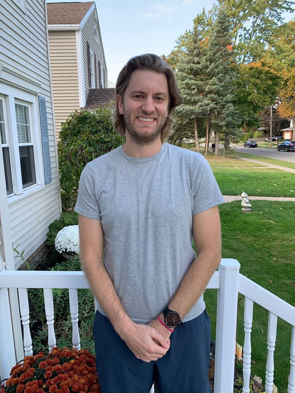Mathew Fox, Recruiter, standing in grey shirt and blue pants on white porch in front of lawn
