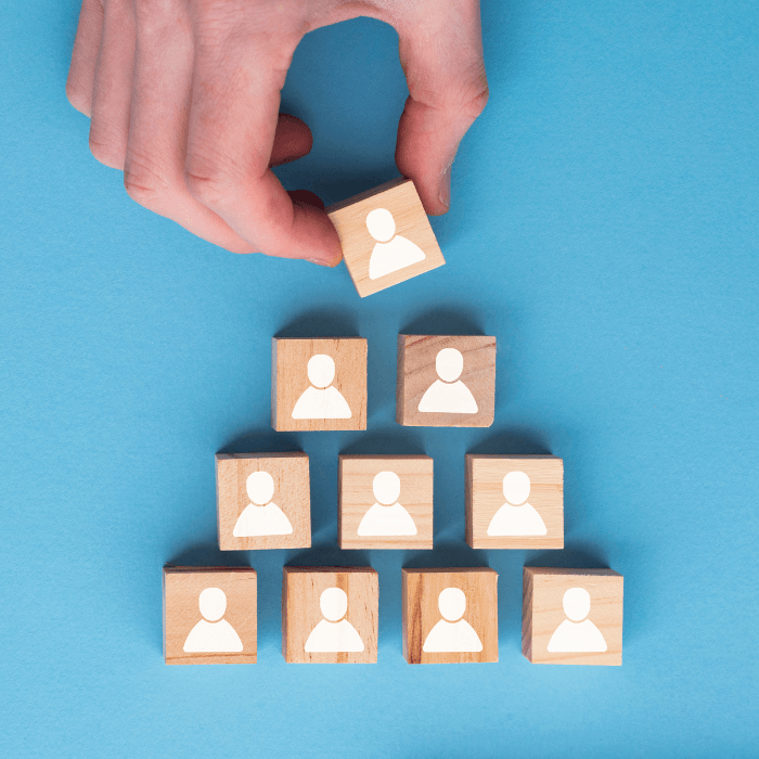 A man's hand places a block at the top of a block pyramid