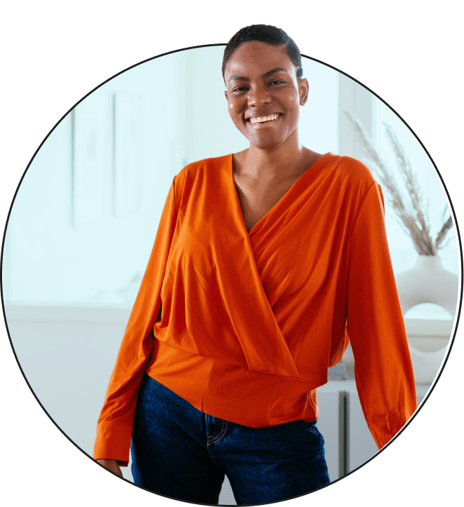 Woman wearing an orange shirt posing and smiling at home.