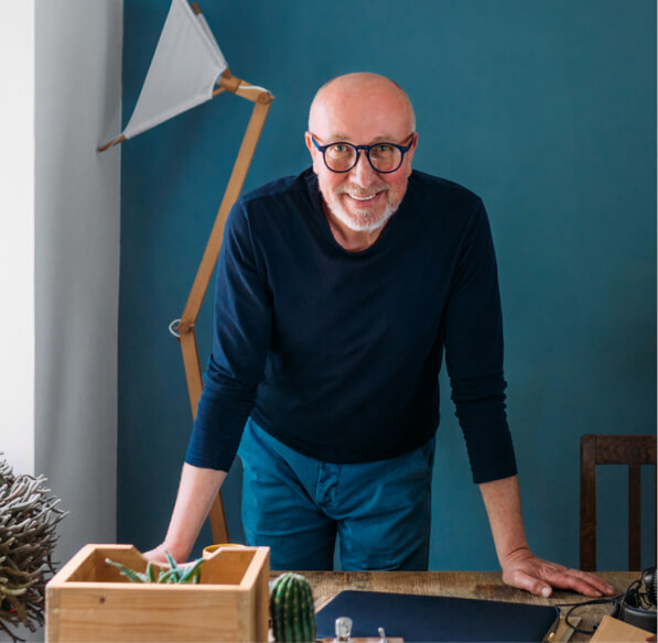 An older man leaning over a desk in a home office.