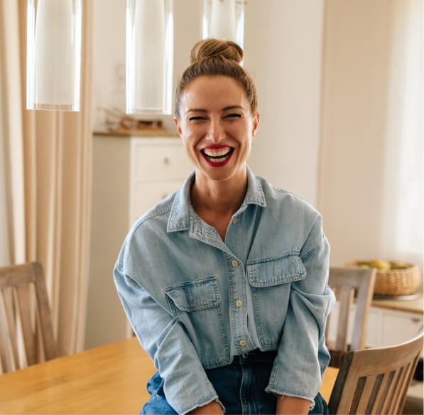 Woman sitting at her kitchen table and laughing.