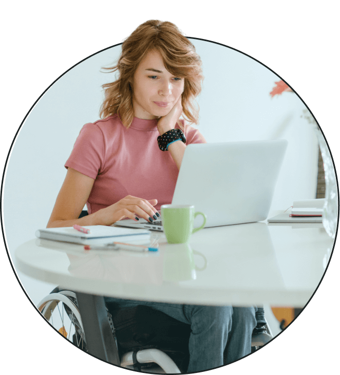 A woman in a wheelchair working on a laptop at a table.