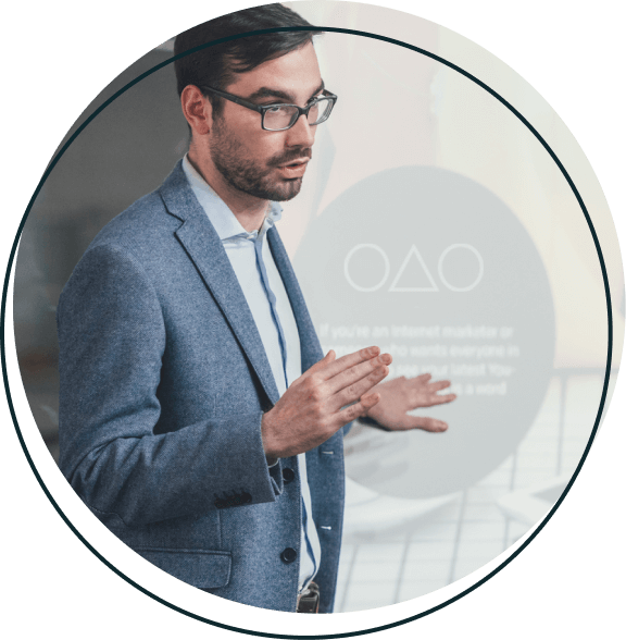 A man in a suit standing up while giving a presentation.