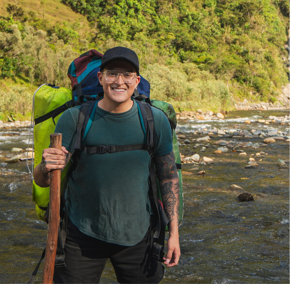 A man on vacation hiking through a river.