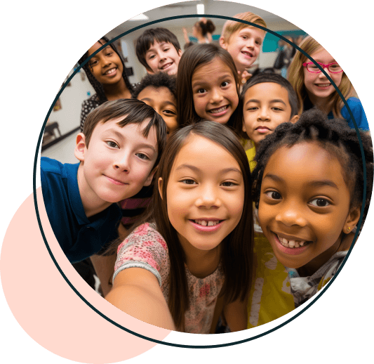 A diverse group of smiling children gathered closely together, posing for a cheerful group selfie in a classroom setting.