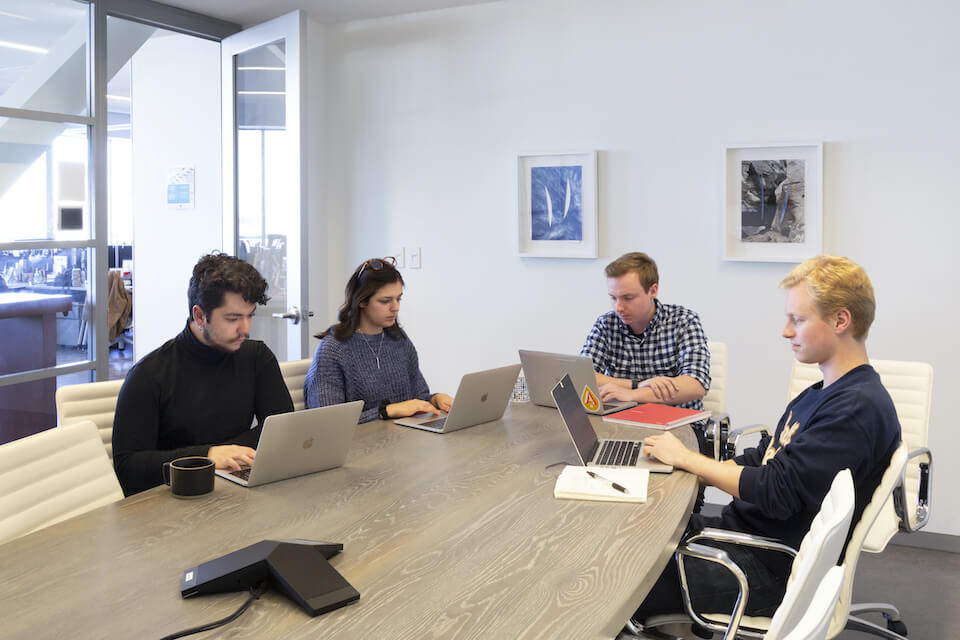 Terakeet employees sitting at conference table in meeting room with Light Work art
