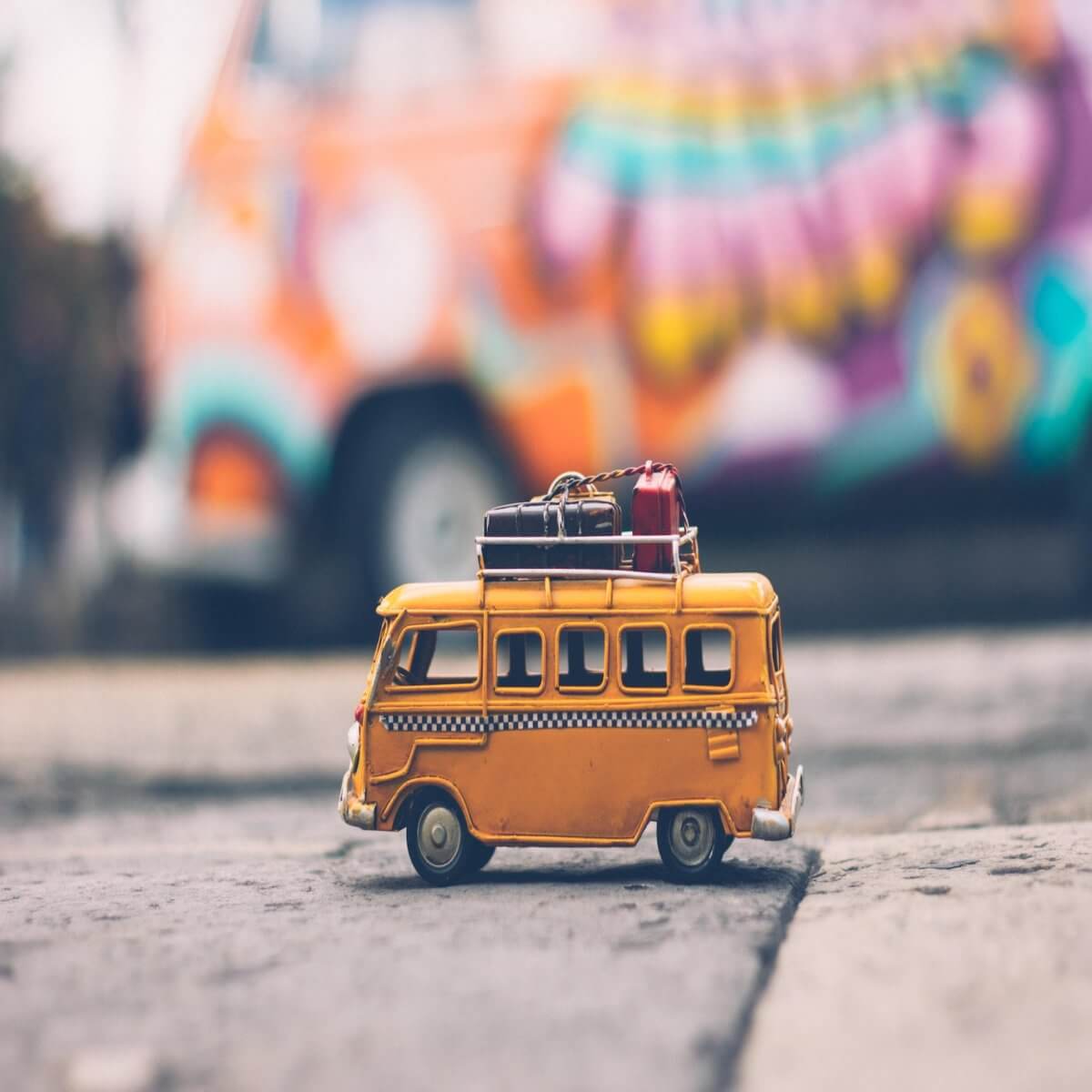 A small, yellow toy bus has a roof rack full of luggage