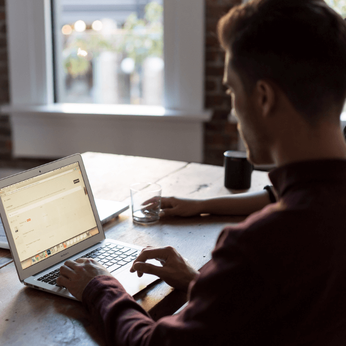 Man sits at a table working from home on his laptop