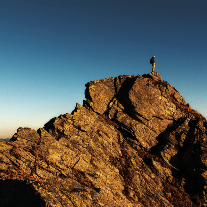 Male backpacker stands at the top of a rock