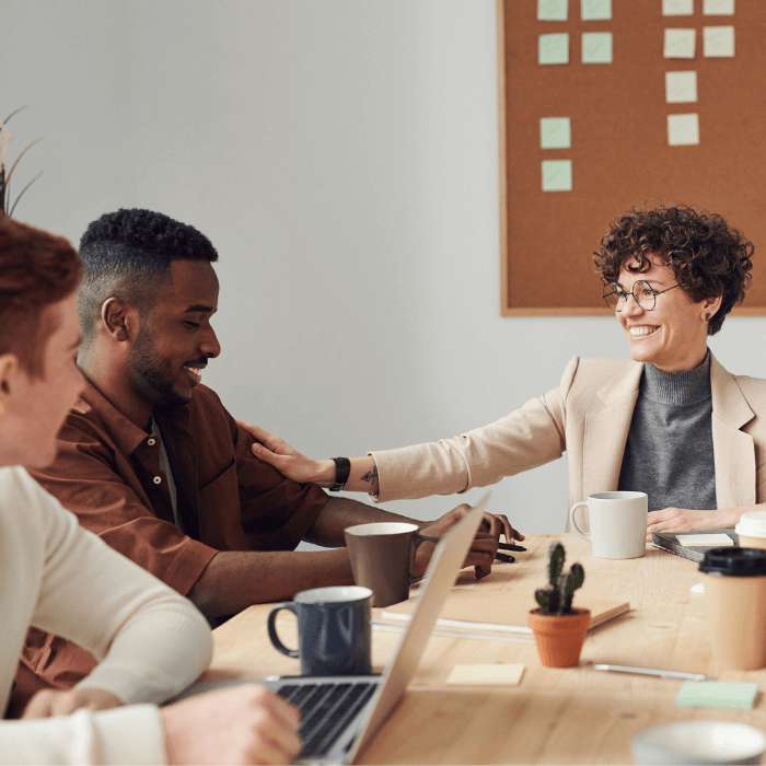 Colleagues smile together at a work desk