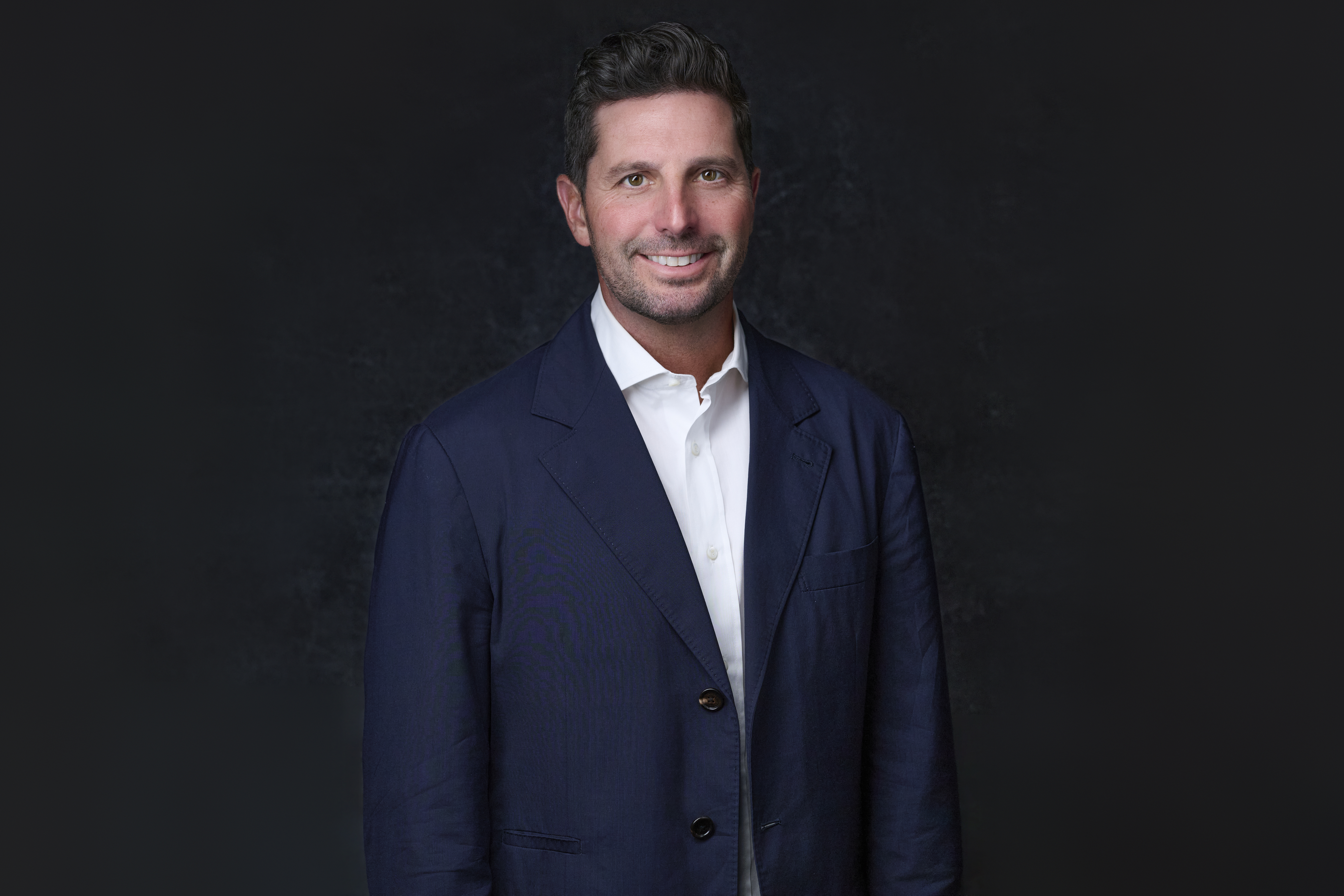 MacLaren "Mac" Cummings stands, smiling in a suit