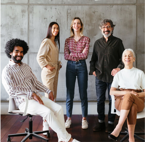 A diverse group of coworkers sitting and standing while posing for a photo.