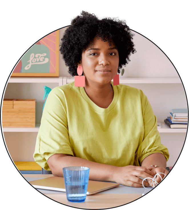 A woman looking straight ahead and sitting at a desk.