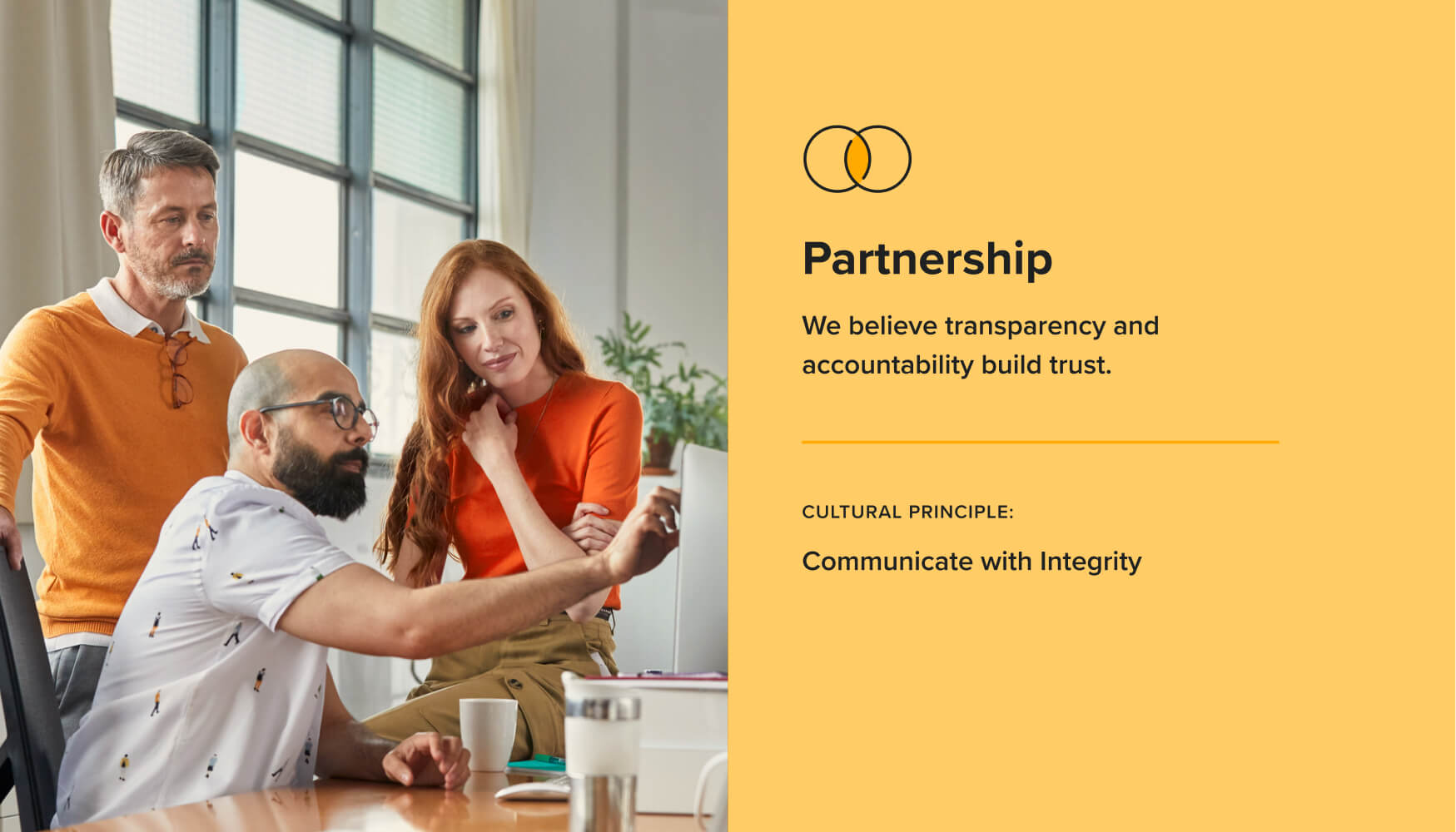 Three adults work around a computer in an office, beside a graphic that describes Terakeet's Partnership value and cultural principle.
