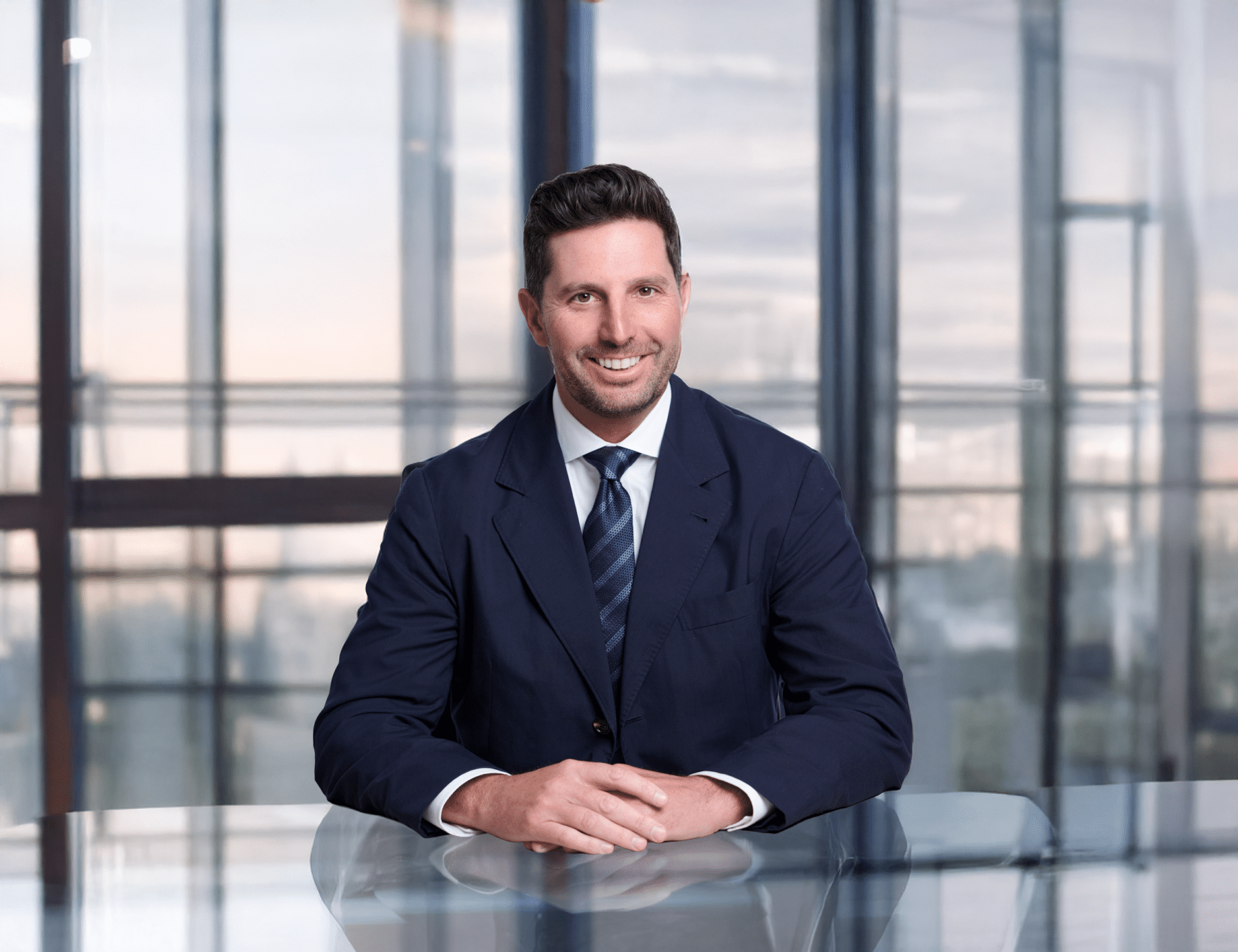 MacLaren "Mac" Cummings smiling in a suit behind a desk