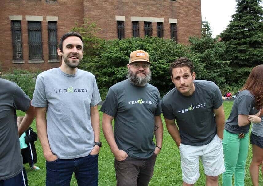 Three people wearing Terakeet shirts smile outside