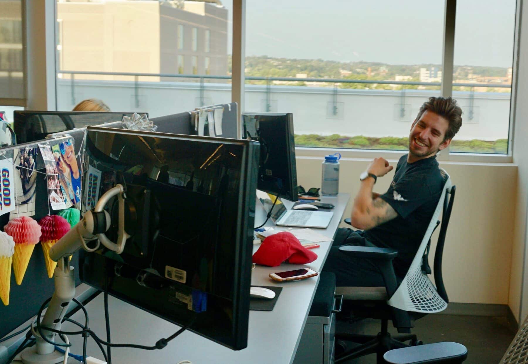 A man sitting at a cubicle smiles