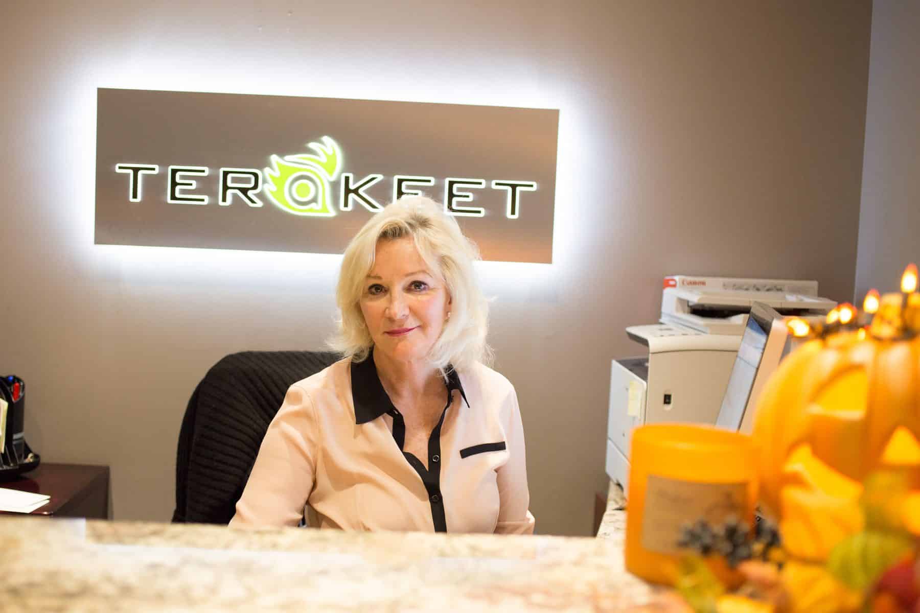 A woman sits at a desk in front of a Terakeet sign
