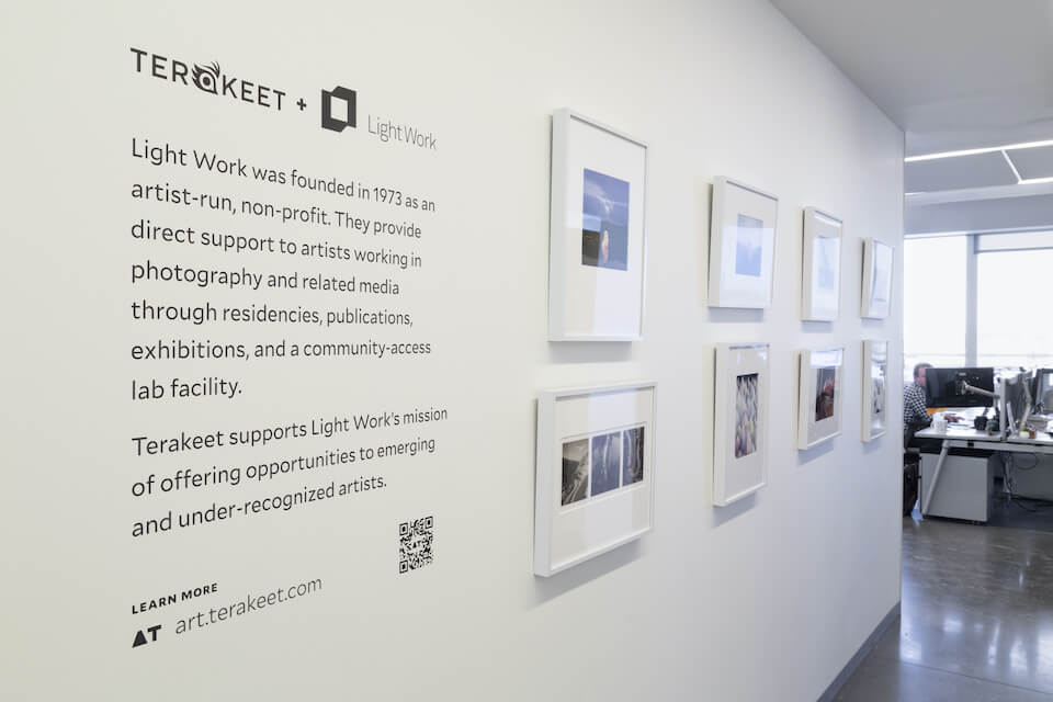 Light work art displayed on wall at Terakeet offices with descriptions and QR code