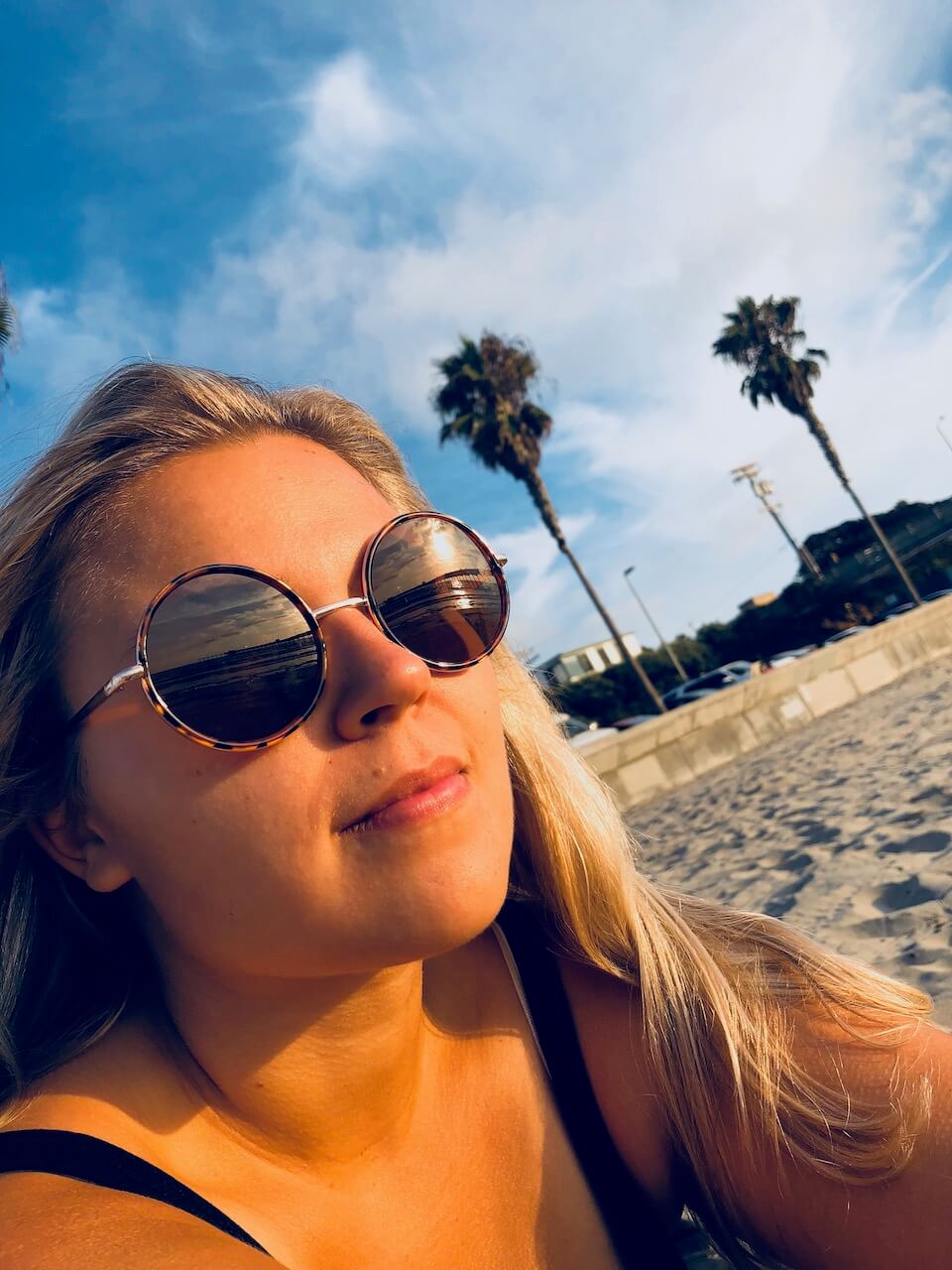 Racheal Morrow, Digital Marketing Specialist, in sunglasses on beach, two palm trees in background
