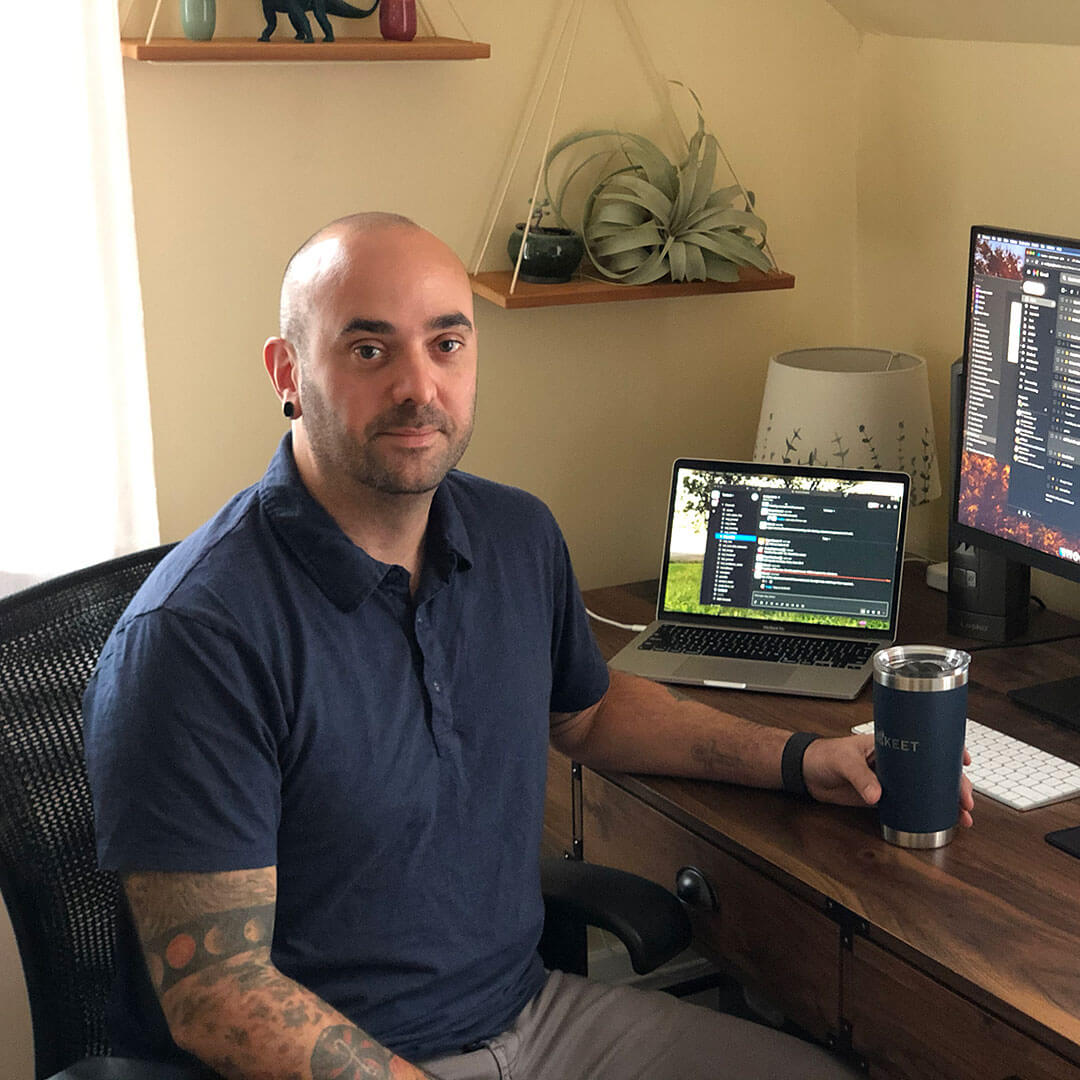 Krispin Dolbear sits at his computer with a mug full of coffee