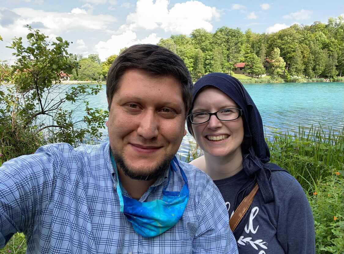 Saj Hoffman-Hussain and his wife smile in front of a beautiful lake!